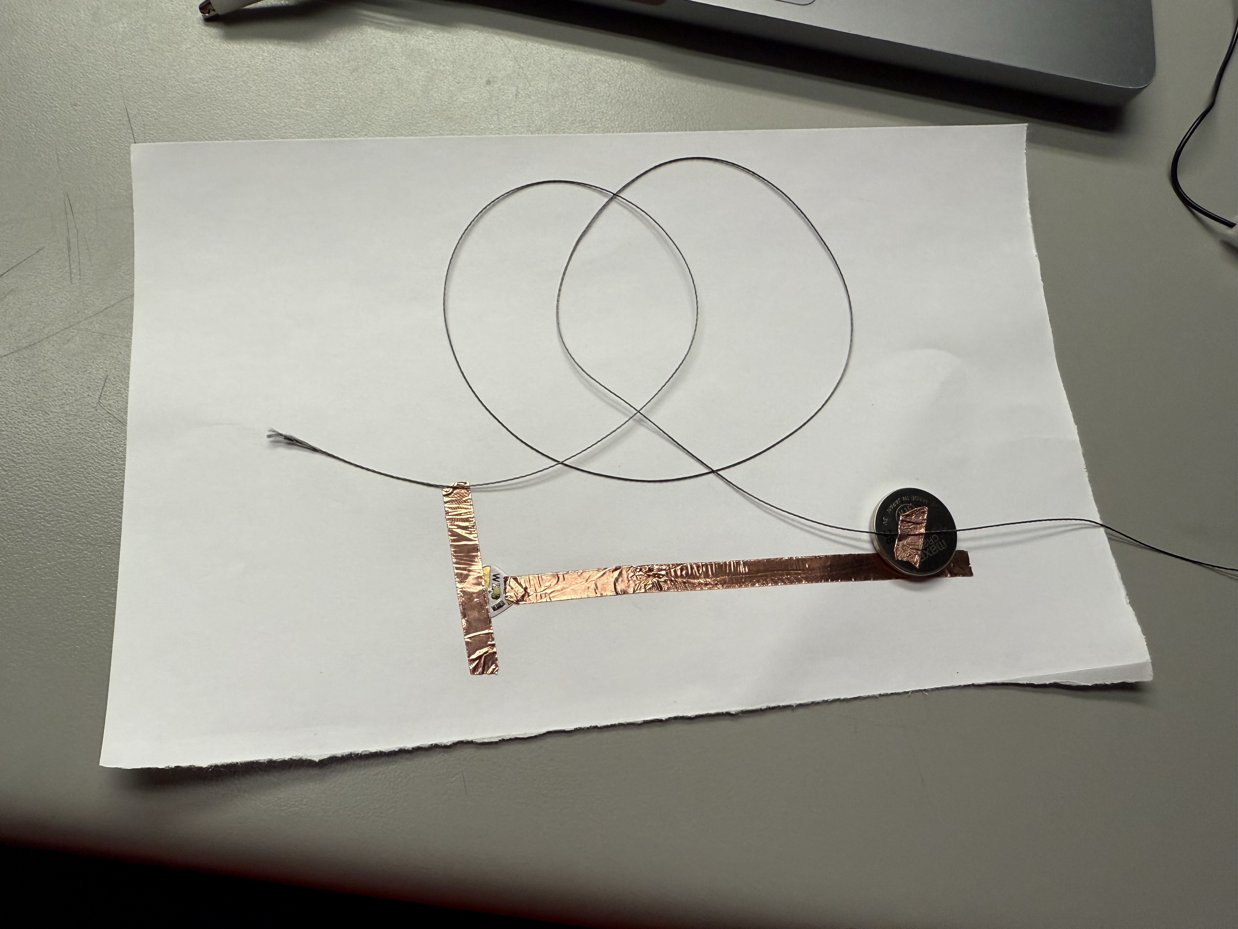 Close-up of a copper tape+Conductive thread circuit and a coin battery.