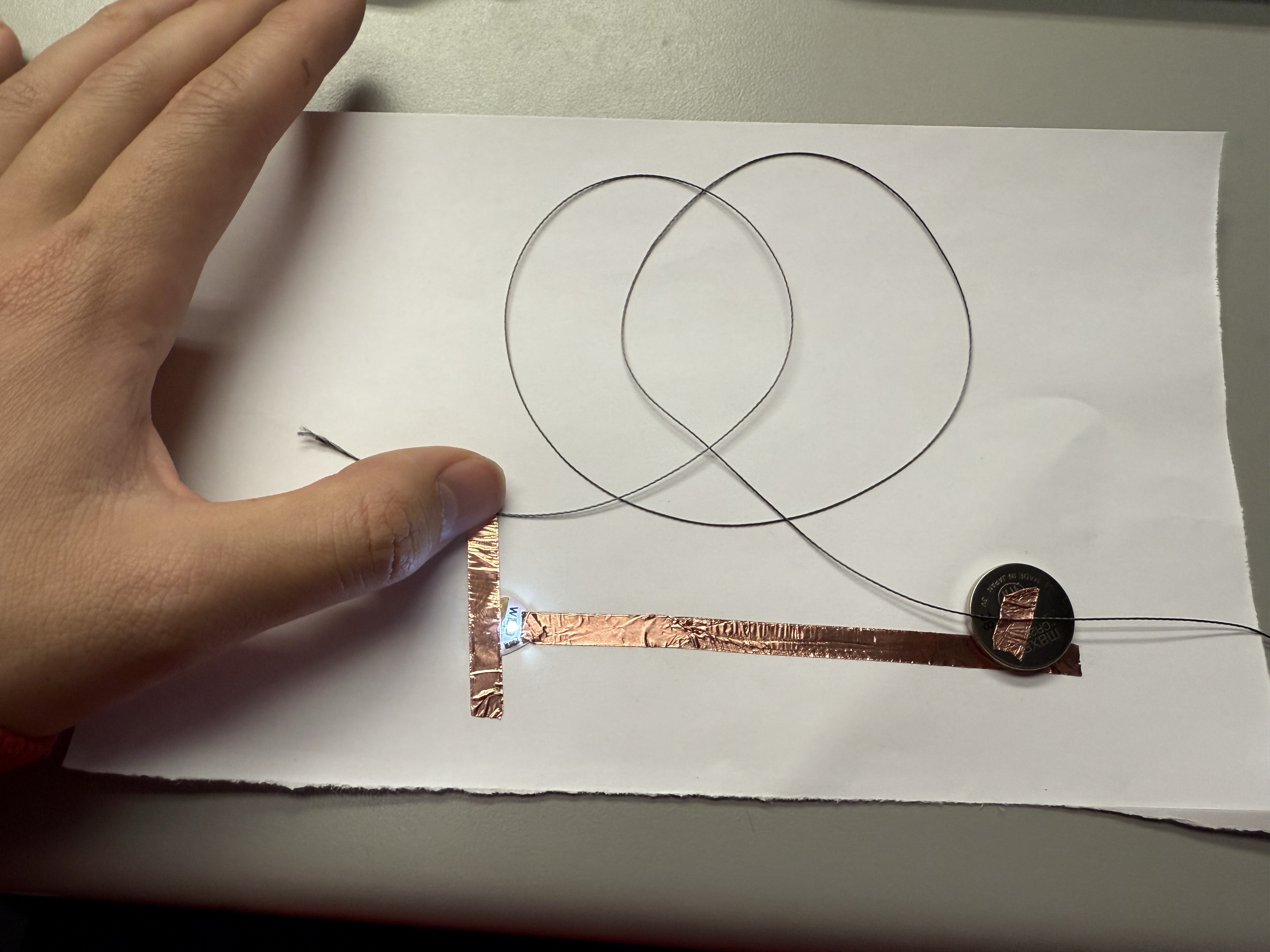 Close-up of a copper tape+Conductive thread circuit powered by a coin battery.