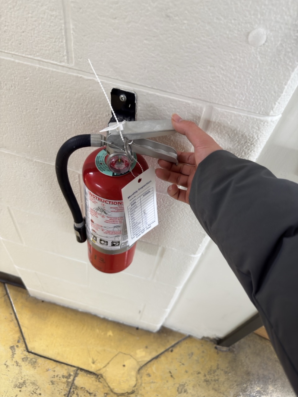 action to gripping the handle of a red fire extinguisher and pressing the lever to release its contents.